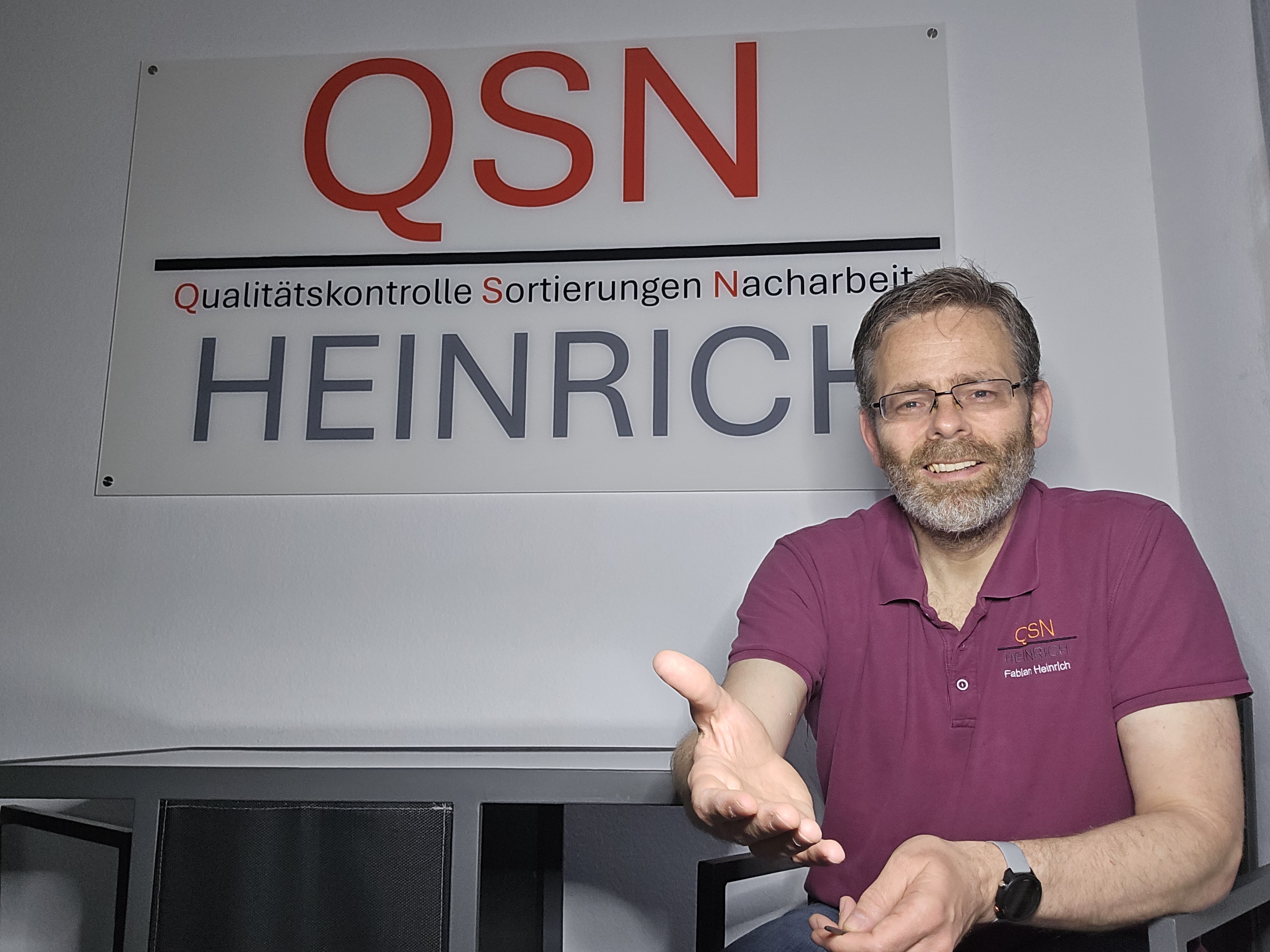 Fabian Heinrich vor dem QSN-Heinrich-Logo